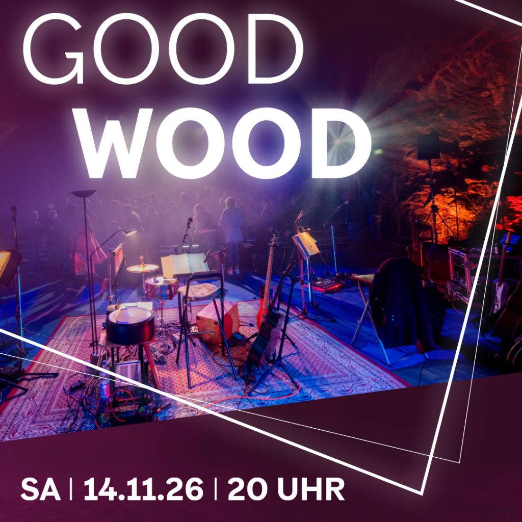 Foto ines Schlagzeugs und Musikern vor Publikum in einem dunklen Raum.